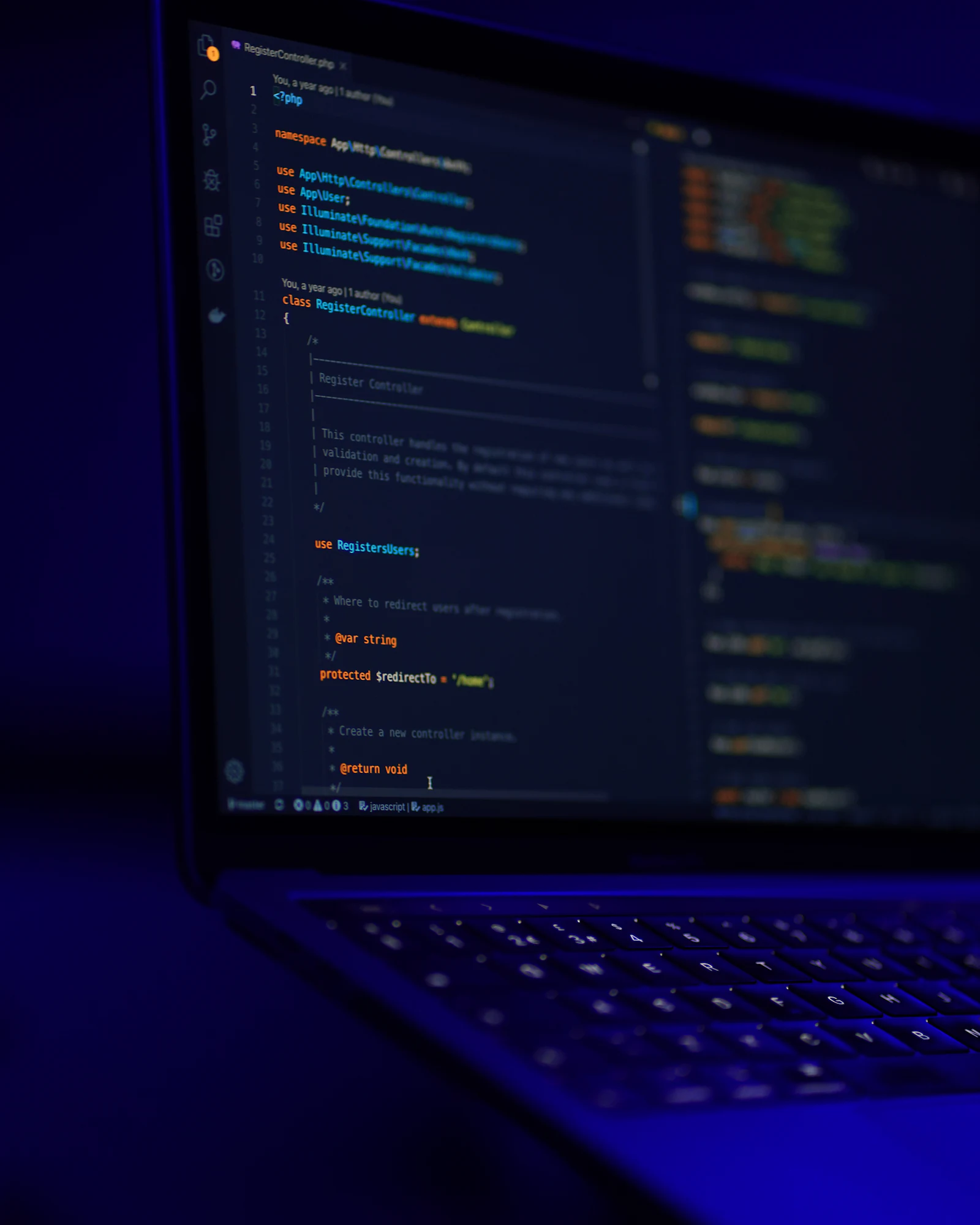 A laptop showing code in an editor, lit in blue