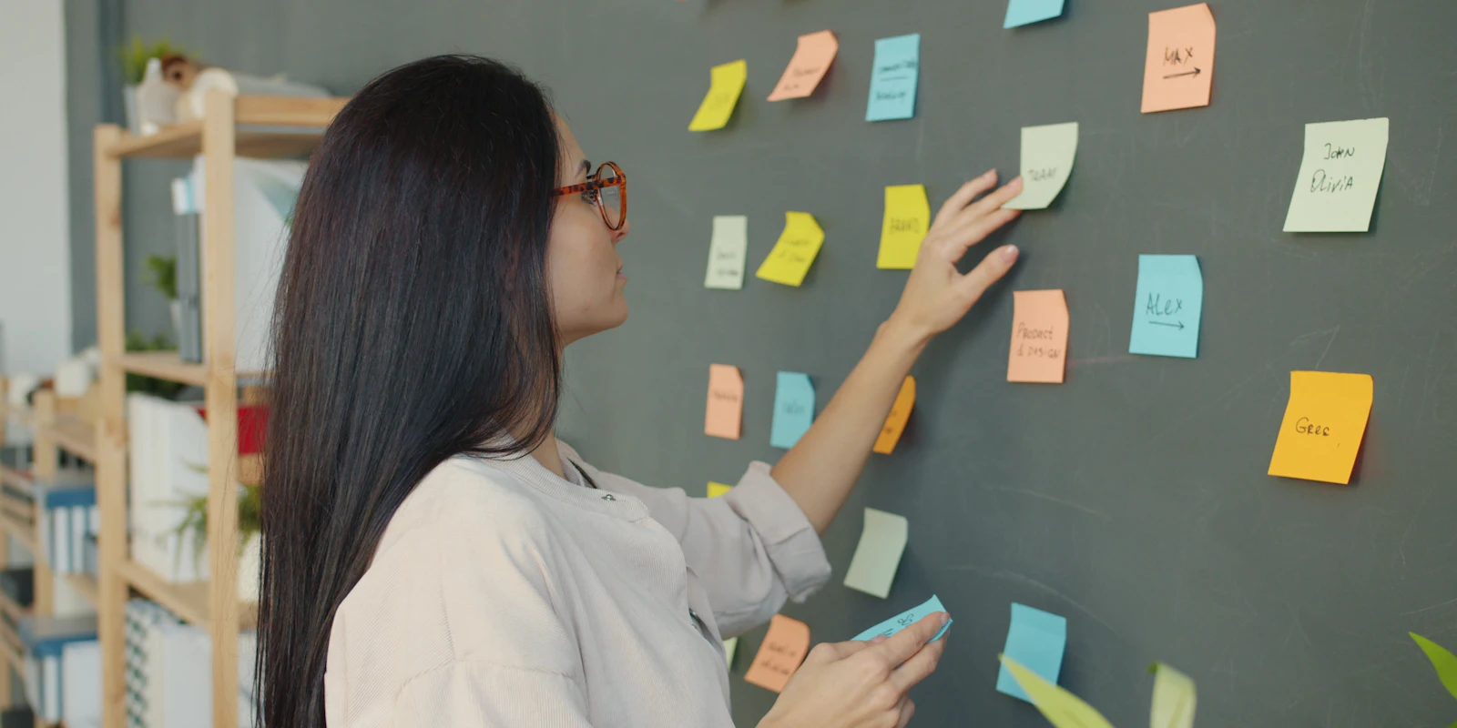 A woman arranging sticky notes on a dark wall