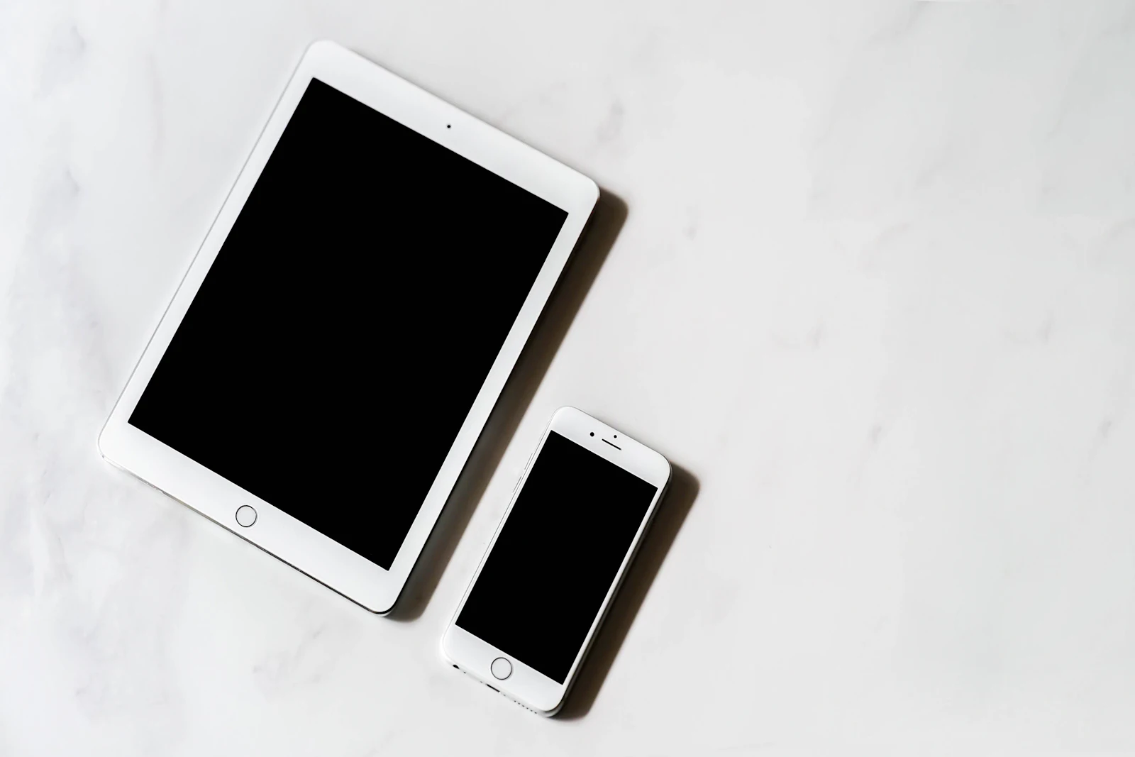 A tablet and a phone side by side on a marble surface